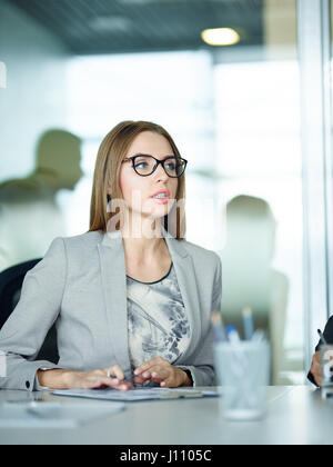 Portrait of beautiful young businesswoman wearing glasses looking confident while sharing ideas on corporate issues and discussing it during meeting i Stock Photo