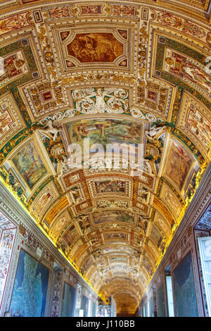Vatican City - June 25, 2015: Beautiful decorated painted ceiling with different scenes and carvings on a long lit hallway in the Vatican Museum Stock Photo