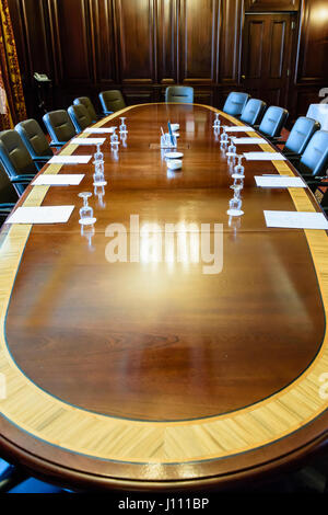 Large wooden table in a board room with wood panelling, set up for a meeting Stock Photo