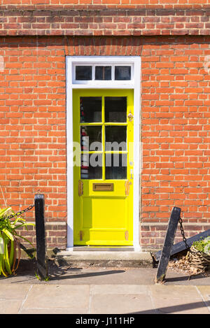 Bright yellow Victorian British front door on a red brick wall Stock Photo