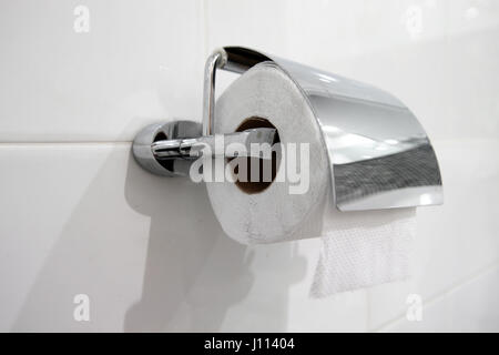 white toilet paper roll hanging on a chrome holder Stock Photo