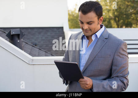 Closeup portrait, man in gray suit blazer doing business on tablet, outside outdoors background Stock Photo