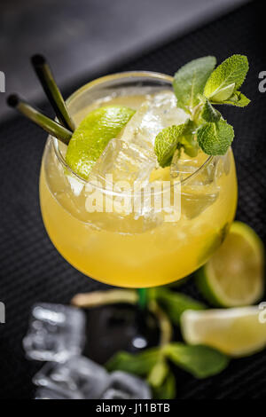 Cocktail is consisting of tequila, freshly squeezed lime juice, mango juice and garnished with a lime slice and mint leaf Stock Photo