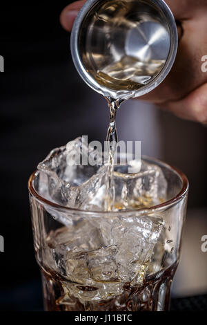 Bartender pouring alcohol in glass, close up shot Stock Photo