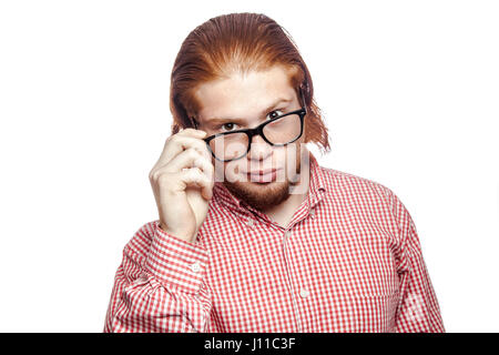 thoughtful thinking bearded readhead businessman with red shirt and freckles holding glasses and looking at camera . studio shot isolated on white. Stock Photo