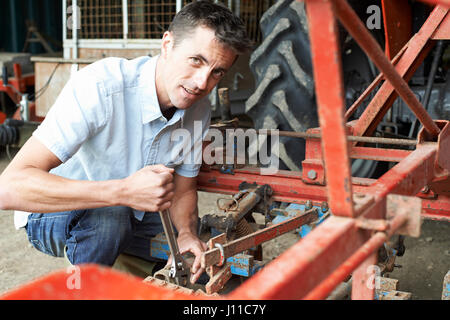 Farmer Working On Agricultural Equipment In Barn Stock Photo