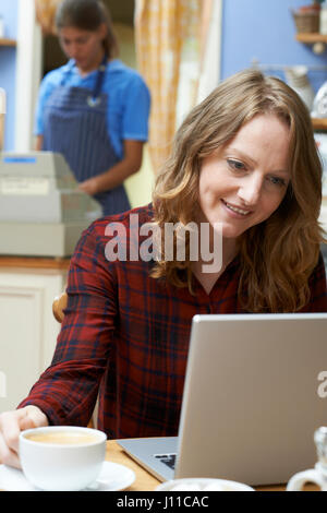 Woman In Coffee Shop Using Laptop Computer Stock Photo