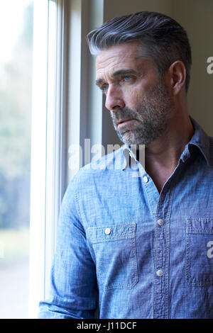 Mature Man Suffering From Depression Looking Out Of Window Stock Photo