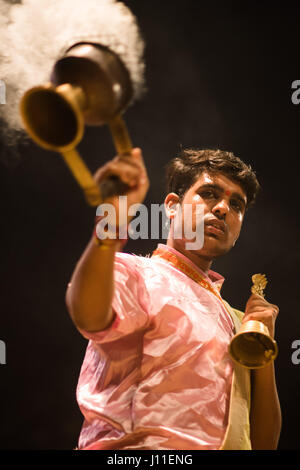 Younf India male priest conducting aarti ritual dedicated to the river Ganges in Varanasi Stock Photo