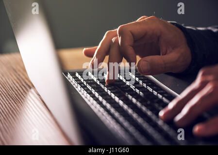 Computer programmer and hacker hands typing laptop keyboard, close up low key with selective focus Stock Photo