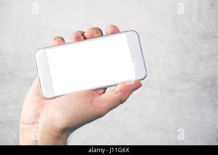 Male hand holding mobile phone with blank mock up screen as copy space, man using modern white smart phone Stock Photo