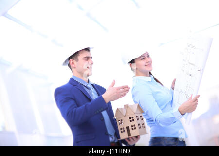 Two colleagues discussing data working and tablet, laptop with on on architectural project at construction site at desk in office Stock Photo