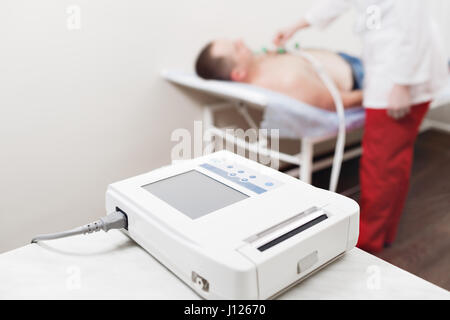 apparatus or device the unit of measurement of the electrocardiogram in a doctor's office. Male patient having ECG electrocardiogram in hospital. selective focus Stock Photo