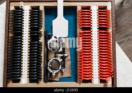 Optometrist prepares a set of ophthalmic trial lenses for vision testing and trial frame, open table with optometric instruments, top view Stock Photo