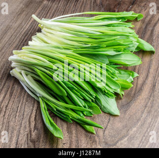 Young fresh wild garlic on the wooden table. Stock Photo