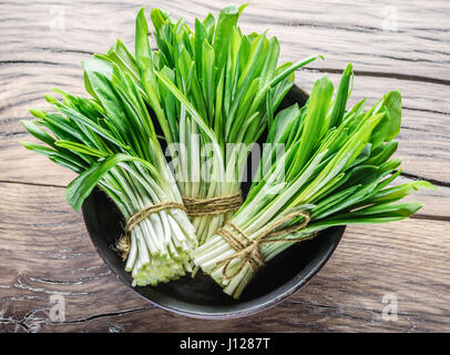 Young fresh wild garlic on the wooden table. Stock Photo