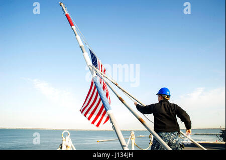 NORFOLK (March 6, 2017) Aviation Ordnancemen 3rd Class Casey Heffron, from Fort Smith, Arkansas, raises the ensign during morning colors aboard the aircraft carrier USS George Washington (CNV 73). George Washington is homeported in Norfolk preparing to move to Newport News, Virginia for the ship’s refueling complex overhaul (RCOH) maintenance. (U.S. Navy photo by Mass Communication Specialist 2nd Jessica Gomez) Stock Photo