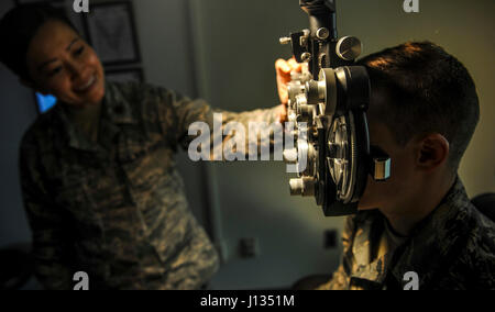 U.S. Air Force Maj. See Vang, 51st Aerospace Medicine optometry flight commander, left, changes lenses on the phoropter while Staff Sgt. River Carson, 8th Medical Operations Squadron public health technician, stares at a letter chart on at Kunsan Air Base, Republic of Korea, March 24, 2017. The phoropter checks for refractive errors in the eyes and assists in eye glass prescriptions.  (U.S. Air Force photo by Senior Airman Colville McFee/Released) Stock Photo