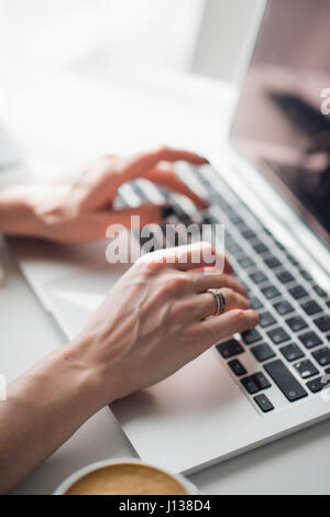 Close-up picture of woman's hands typing a message on her laptop during lunch. Stock Photo