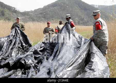 Soldiers from 25th Transportation Battalion and 2nd Infantry Division Sustainment Brigade work to recover the parachute from a low cost aerial delivery system, April 12, 2017, at a drop zone between Daegu and Busan, South Korea. Multiple U.S. assets and ROK Air Force validated their aerial logistics capabilities as part of ongoing exercise Operation Pacific Reach ’17. Stock Photo