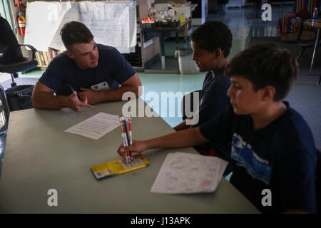 KAILUA, Hawaii – Lance Cpl. Malsky Kennan, a ground electronics telecommunications and information technology systems maintainer with Headquarters Battalion, Marine Corps Base Hawaii, assists students with classwork at Kailua Intermediate School, April 12, 2017. Marines gave back to their community by volunteering at KIS for the school’s “Wednesday Volunteer Program.” The program provides Marines the opportunity to interact with students, assist teachers around the classroom, and be positive role models for the children. (U.S. Marine Corps Photo by Cpl. Jesus Sepulveda Torres) Stock Photo