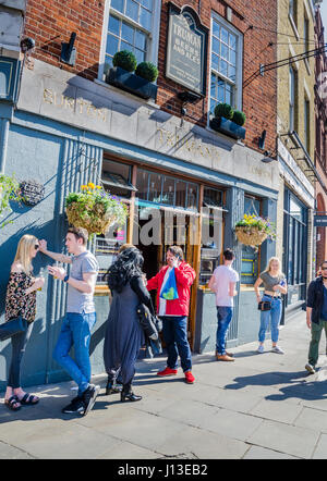 People stand outside a Burton Truman's pub in East London. Stock Photo