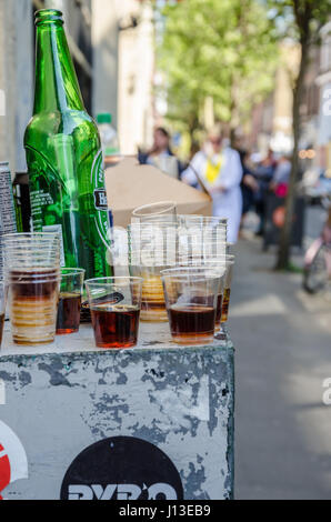 Empty beer bottles and plastic shot glasses left abandoned on a ledge outside in the street. Stock Photo