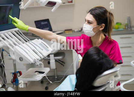 Female Dentist showing woman's teeth on the screen Stock Photo