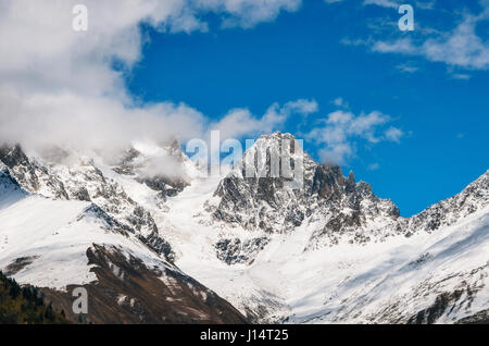 Snow covered mountains and their peaks in the clouds against the blue sky in Georgia. Greater Caucasus Mountains Stock Photo