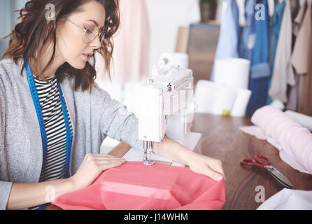 Skilled young tailor sewing on machine Stock Photo
