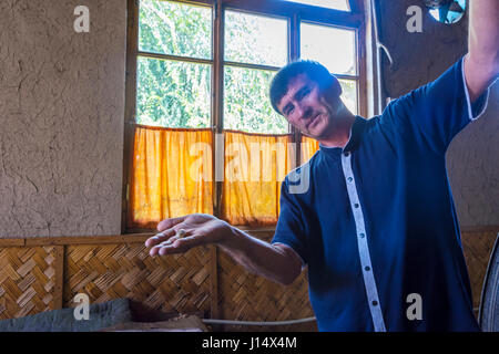 MARGILAN, UZBEKISTAN - AUGUST 20: Man showing silk thread coming from a silkworm cocoon in a silk factory. August 2016 Stock Photo