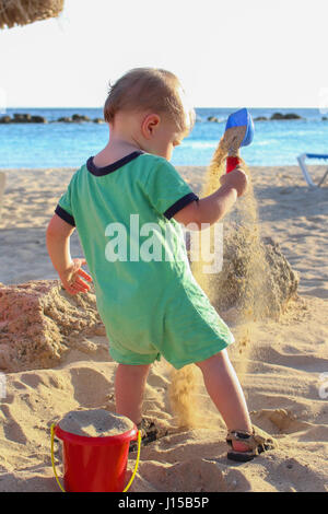 toddler boy playing with sand at the beach Stock Photo