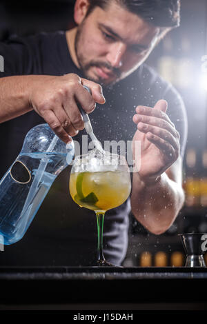 Bartender is pouring soda water, he is preparing a mango cocktail Stock Photo