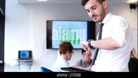 Businessman using tablet computer in office with coworkers in background Stock Photo