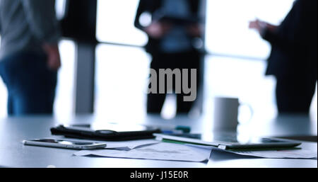 Devices on table with business people in background in modern office building Stock Photo