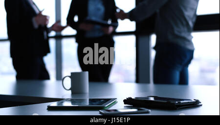 Devices on table with business people in background in modern office building Stock Photo