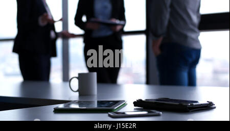 Devices on table with business people in background in modern office building Stock Photo