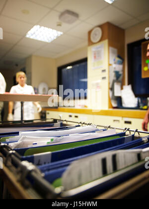 Patient notes with medical staff walking in background  on busy ward in large general hospital Stock Photo