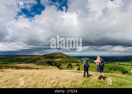 Walkers on Willstone Hill, with Caer Caradoc in the distance, in the Hope Bowdler hills, near Church Stretton, Shropshire, England, UK. Stock Photo