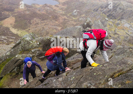Hikers climbing rocks on Daear Ddu east ridge on Carnedd Moel Siabod mountain in mountains of Snowdonia National Park. Capel Curig Conwy Wales UK Stock Photo