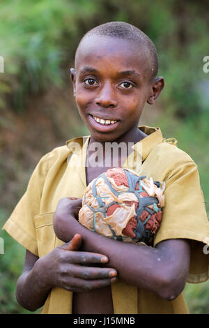 Young boy (12 years) with his self-made football made of fabric scraps and plastic bags in a village near Ruhengeri, Rwanda, Africa Stock Photo