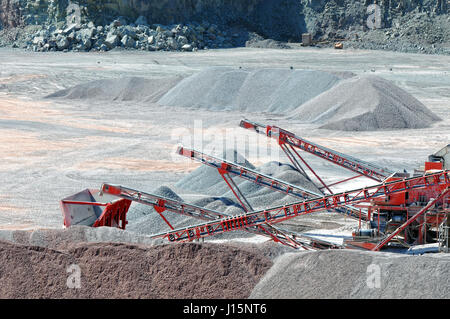 View into a quarry mine of porphyry rock. Crusher and conveyor belts sorting stones. Stock Photo