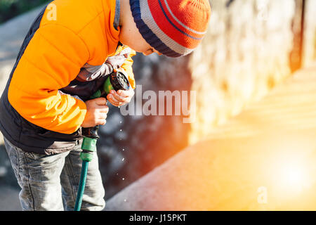 Little boy watering flowers with sunset background Stock Photo