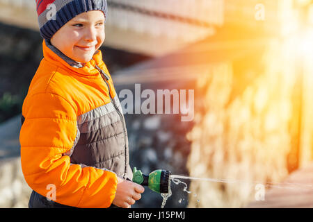 Little boy watering flowers with sunset background Stock Photo