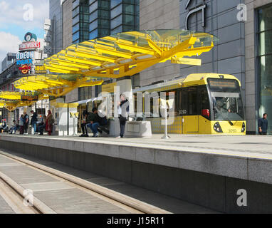 Exchange Square in the centre of Manchester, England, showing people on the tram platform, with the colorful Printworks building in the background. Stock Photo