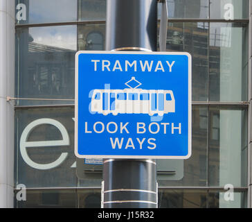 Warniing sign next to the Metrolink tram tramway lines, outside Next in Manchester city center centre. Tramway look both ways. Stock Photo
