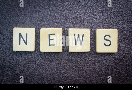 News word concept wood pieces on brown leather Stock Photo