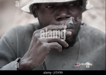An artisanal rose quartz miner takes a break from his labour near Mzimba, Malawi Stock Photo