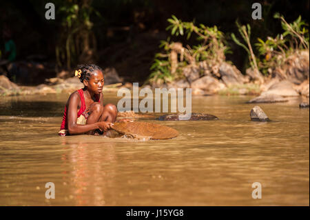 A schoolgirl pans for gold in the mountains near Ankavandra, Madagascar Stock Photo