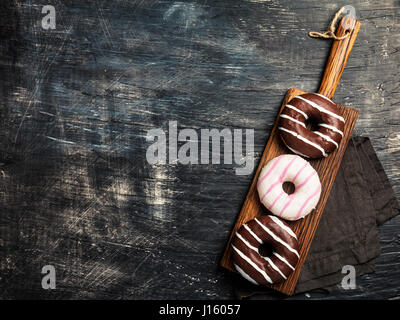 Donuts on cutting board over black background. Top view with copy space Stock Photo